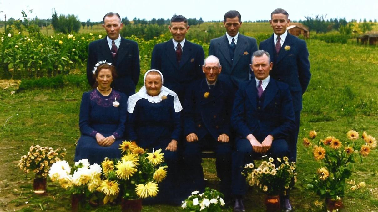 Ingekleurd groepsportret van acht familieleden, genomen op 25 september 1945 achter het ouderlijk huis aan de Westenbergstraat in Wilsum ter gelegenheid van het 40-jarig huwelijk van Albert Heldoorn sr. en Dirkje van de Wetering.
